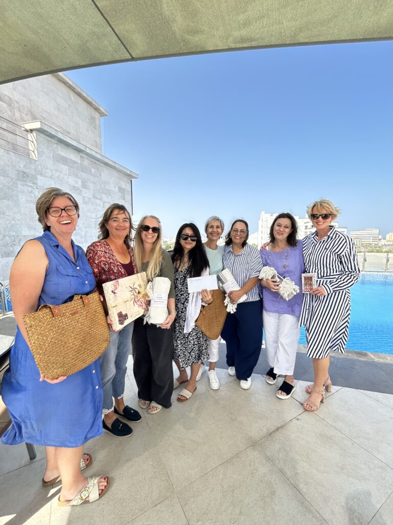 WGO members at a ladies event in Muscat, gathered poolside with prizes and gifts