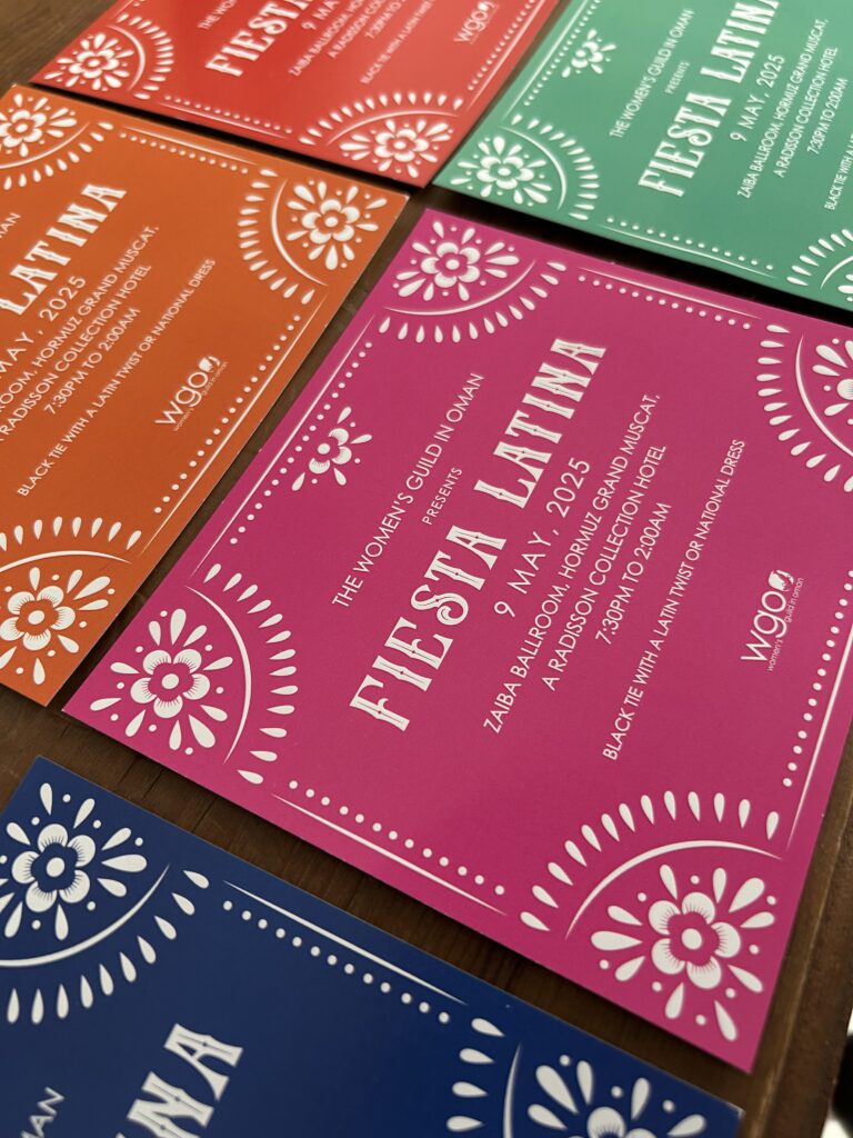 Colourful WGO Fiesta Latina event invitations spread across a table