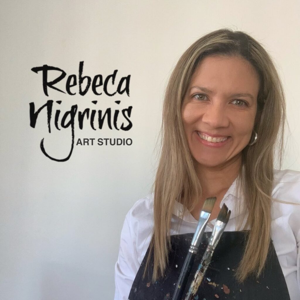 Rebeca Nigrinis, Colombian contemporary artist based in Muscat, holding paintbrushes in her Qurum art studio