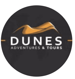 Circular dark logo for Dunes Adventures and Tours with gold dune and mountain illustration and white lettering, based in Al Khuwair, Muscat